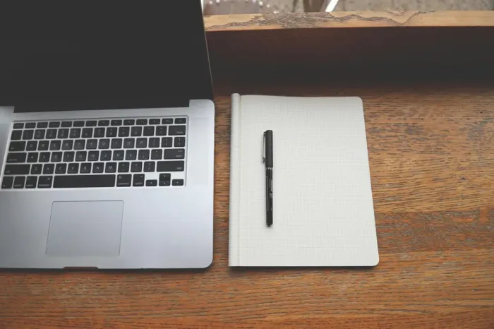 Profesional muda meninjau draf tulisan di laptop dengan catatan kerja di meja
