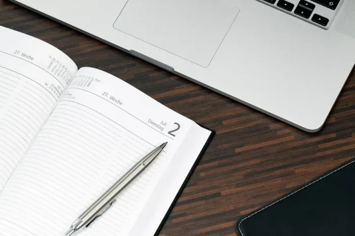Agenda mingguan dan laptop untuk membagi waktu menulis menjadi sesi singkat.