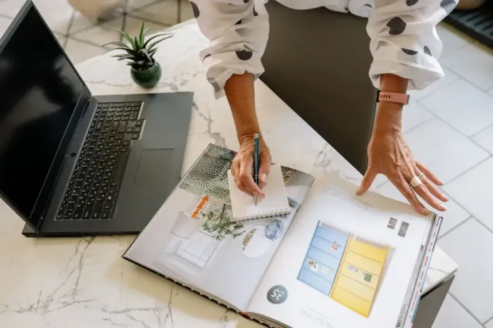 Tangan profesional merencanakan langkah karier di samping laptop dan portofolio