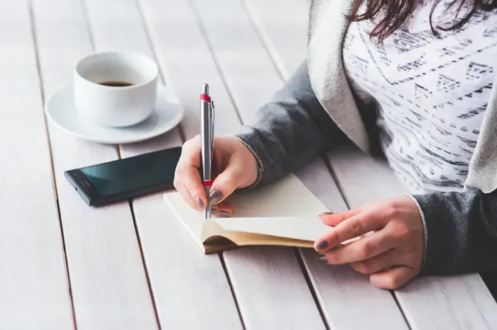 Notebook dan laptop tersusun di meja untuk merencanakan tulisan dengan cermat.