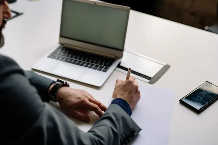 Profesional menyiapkan draf artikel di laptop dan ponsel