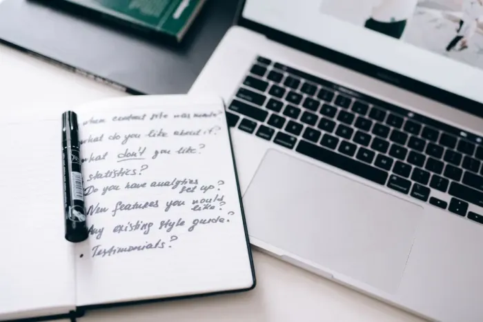 Blogger merencanakan topik tulisan di buku catatan dan laptop