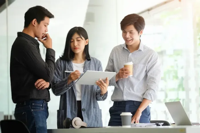 Profesional muda menyusun tulisan kerja di laptop dan buku catatan