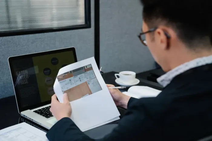Profesional membandingkan laporan di laptop dan catatan kerja