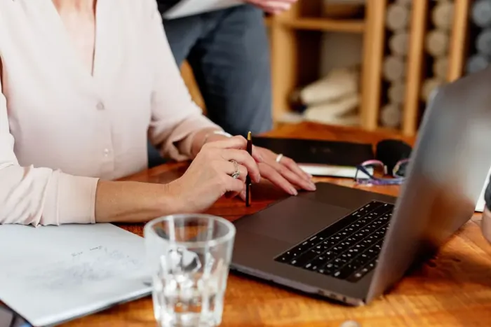 Business owner menulis penjelasan produk di laptop dengan contoh kemasan di meja